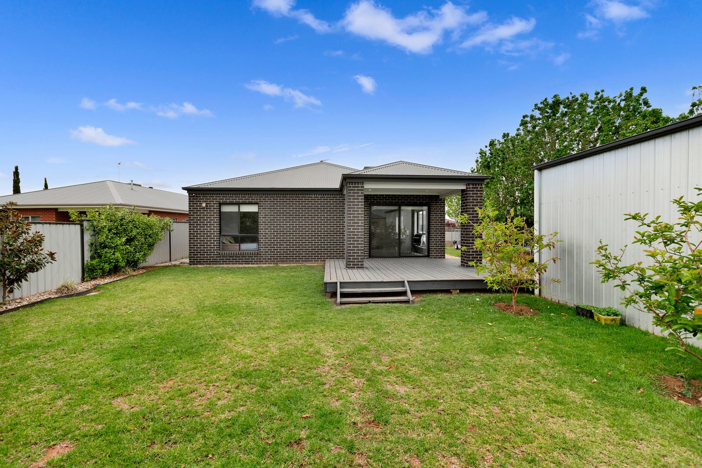 Rear lawn looking towards the home and deck, with the shed to the side
